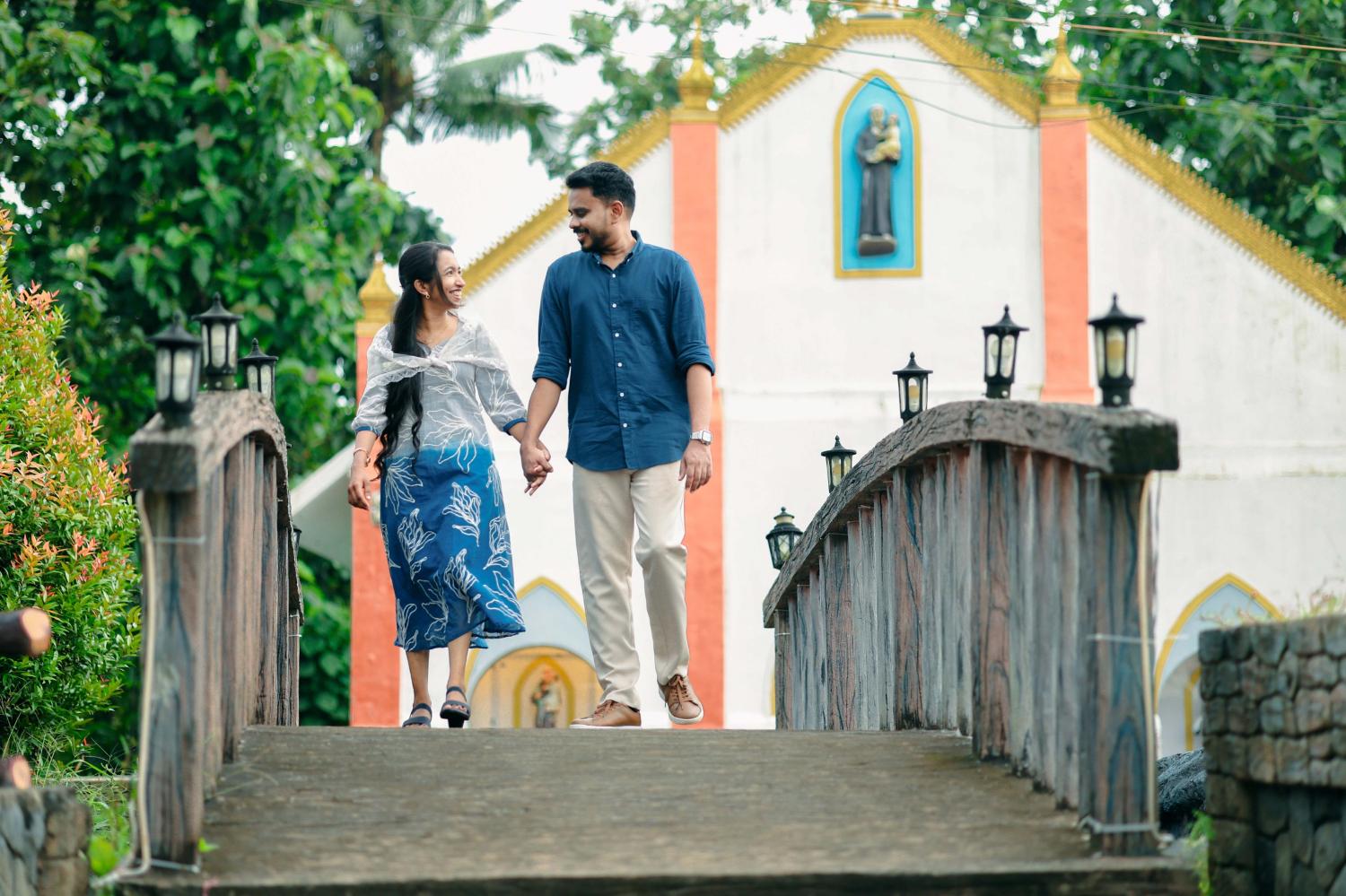 Joji and Bismi walking hand in hand across the church bridge